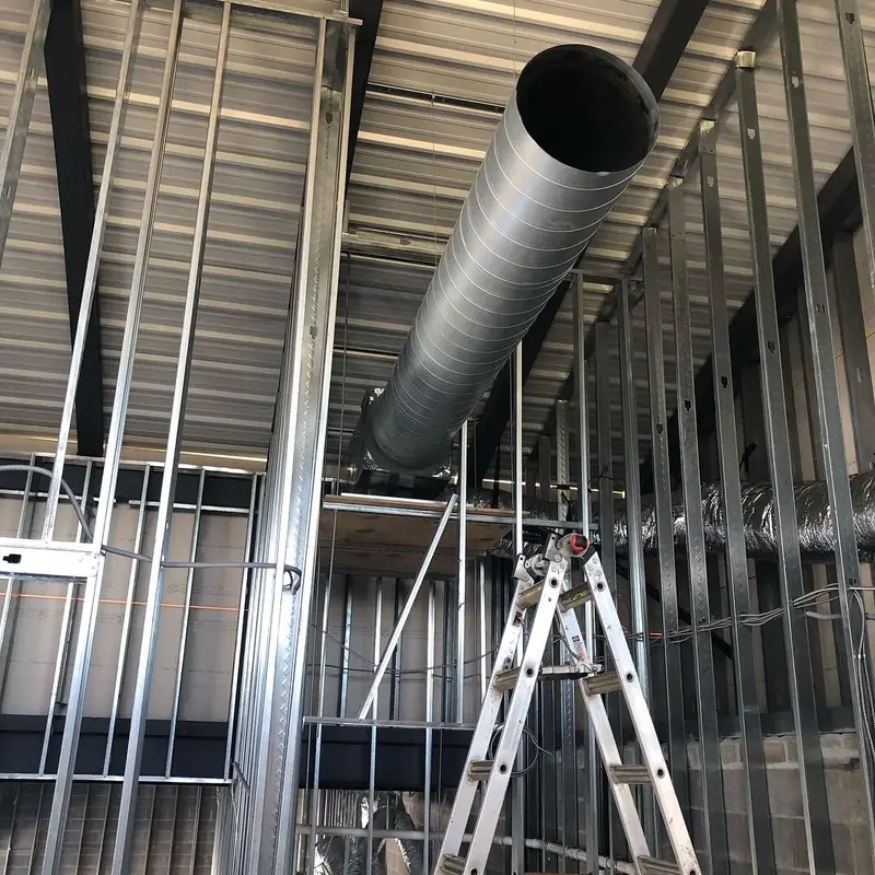 Spiral duct being hung under a steel-framed commercial roof